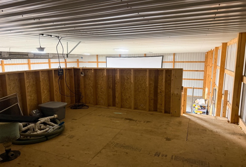 Spacious loft area featuring wood-finish flooring, exposed wood framing, and a white projection screen