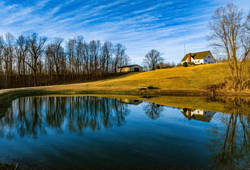 A tranquil pond reflects the surrounding landscape, featuring a gently sloping, expansive lawn