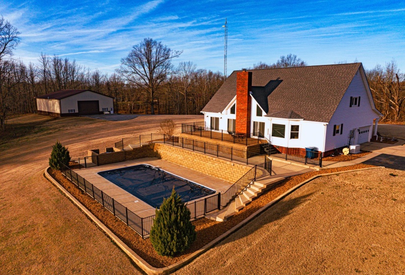 Hillside property featuring an in-ground swimming pool with perimeter fencing, a multi-level deck, an attached two-car garage, and a detached outbuilding