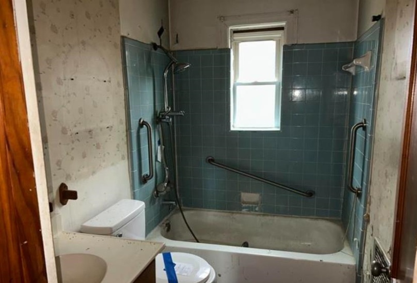 Bathroom featuring a tiled shower surround, built-in bathtub, and window