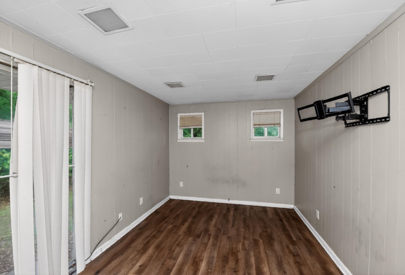 Room featuring wood-finish flooring, light grey paneled walls, and a white drop-panel ceiling with recessed lighting