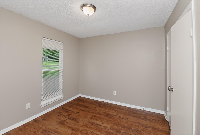 Room featuring wood-finish flooring, neutral-toned walls, and a recessed window with blinds