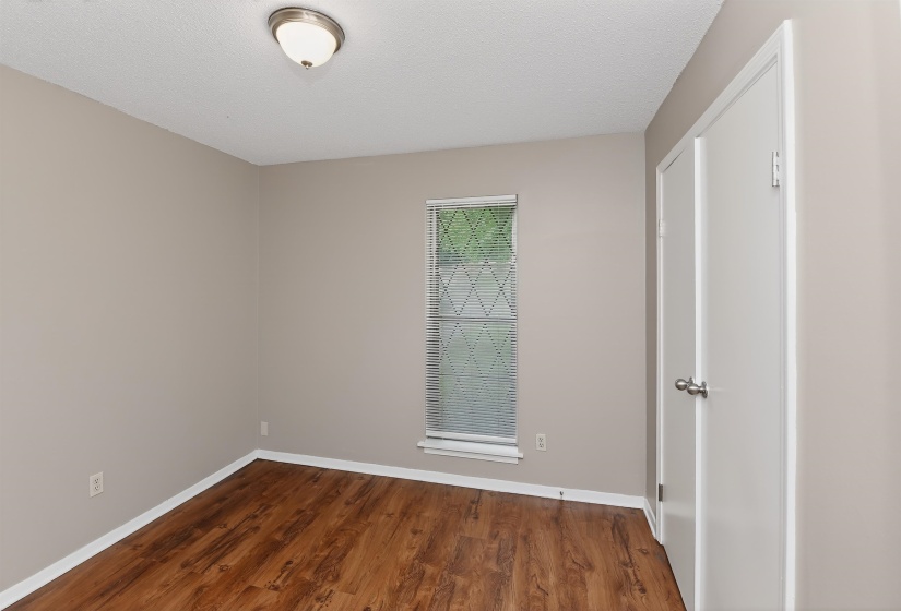 Room featuring wood-finish flooring, a neutral wall color, and a window with blinds