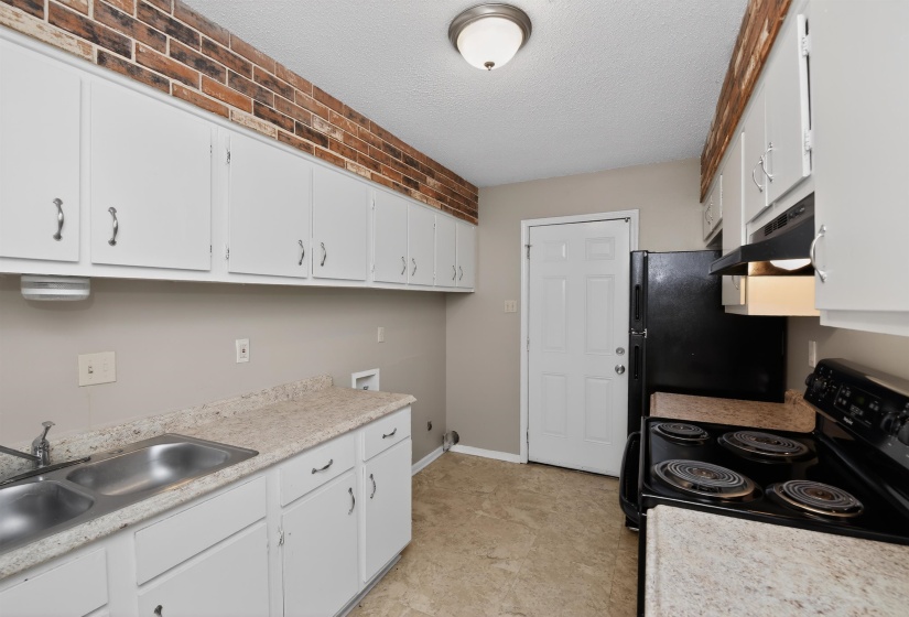 Kitchen featuring white cabinetry, a double basin stainless steel sink, black electric range with overhead microwave, and a black refrigerator