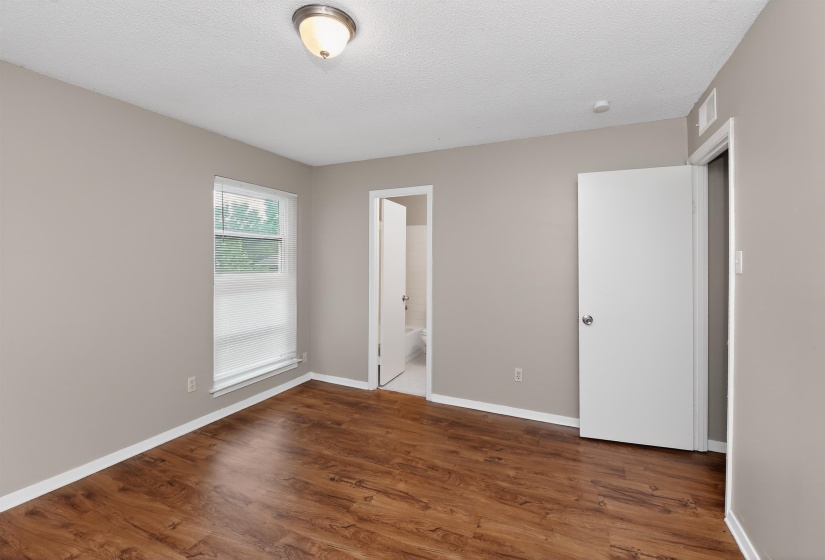 Spacious room featuring wood-finish flooring, neutral-toned walls, and a window providing natural light