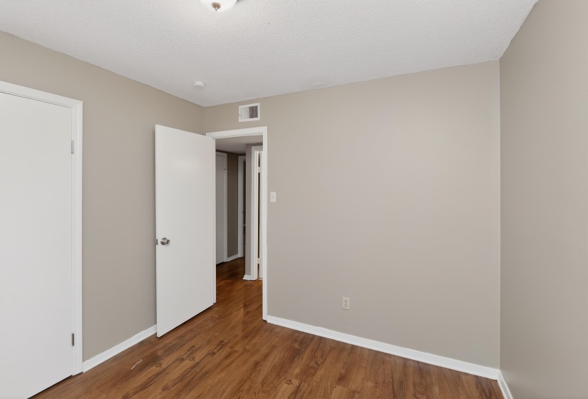 Room featuring wood-finish flooring, light neutral wall paint, white trim, and a white ceiling with a flush-mount light fixture