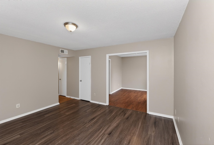 Spacious interior room featuring wood-finish flooring, neutral wall tones, and white baseboards