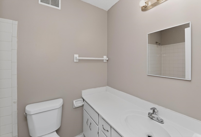 Bathroom featuring a white vanity with integrated sink, chrome faucet, wall-mounted mirror, and neutral wall paint