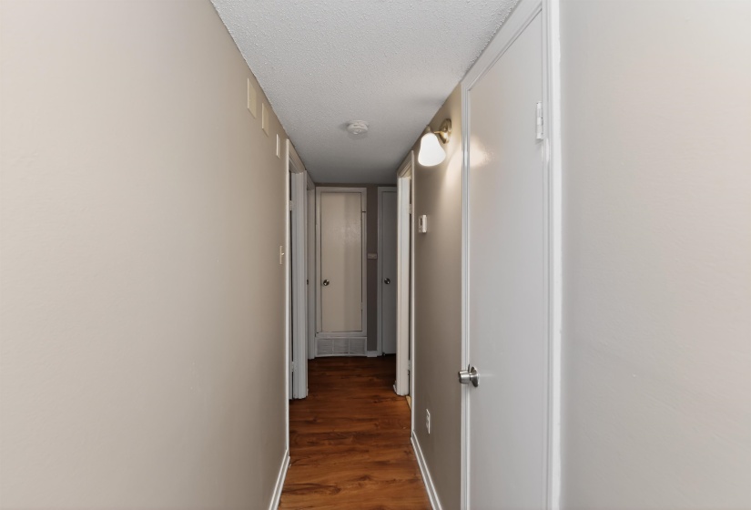 Interior hallway featuring wood-finish flooring, light-toned walls, and multiple white panel doors