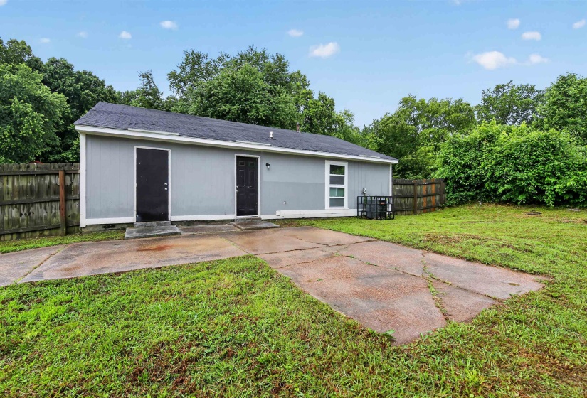 Rear exterior showcasing a light grey siding, two dark entry doors, and a partial wood fence