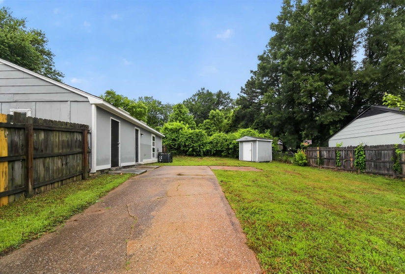 Expansive exterior with a concrete driveway, a separate storage shed, and mature perimeter trees