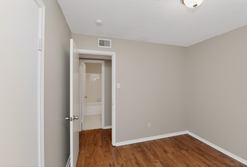 Warm wood-finish flooring complements the light wall color in this room, featuring white baseboards and trim