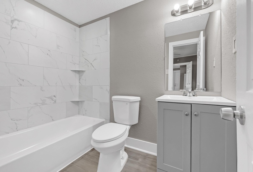 Full bathroom with a tub/shower combination, white-patterned tile surround, and built-in shower niches