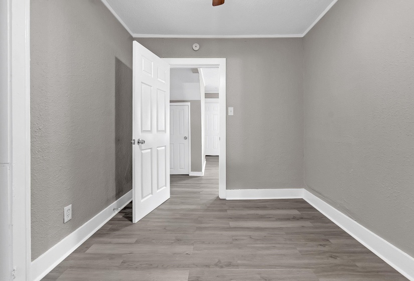 Room featuring wood-finish flooring, light gray walls, and white trim