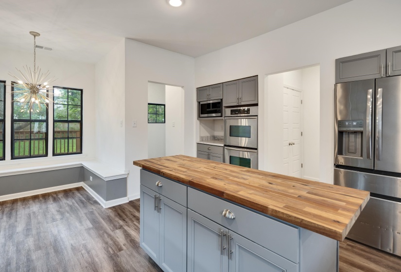 Kitchen and dining area featuring a central island with a wood-finish countertop, stainless steel appliances, and grey cabinetry