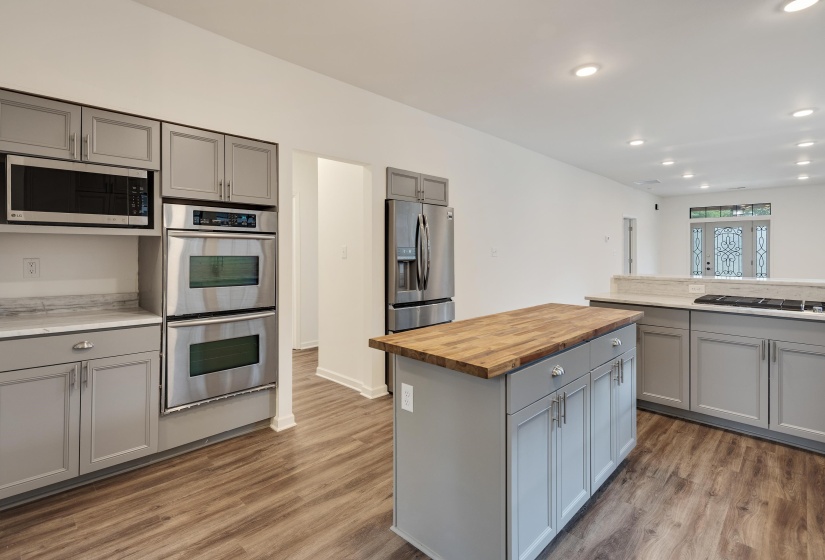 Modern kitchen featuring gray cabinetry, stainless steel appliances, a wood-finish island countertop, and light-toned countertops