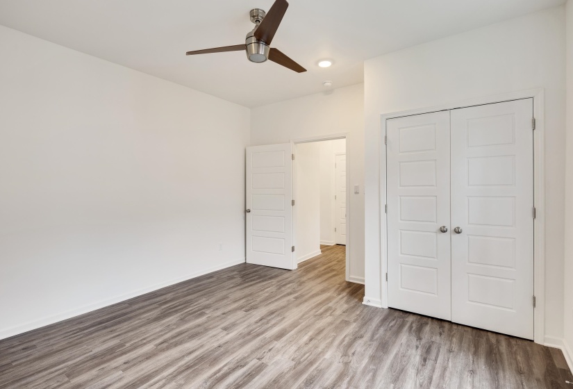 Room featuring wood-finish flooring, a modern ceiling fan, recessed lighting, white walls, and a double-door closet with paneling