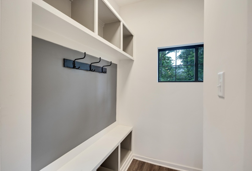 Built-in entryway storage with open shelving, integrated bench seating, and a wall-mounted coat rack