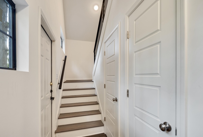 Staircase featuring wood-finish treads, white risers, and a dark metal handrail