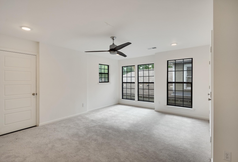 Bright room featuring light gray carpeting, crisp white walls, recessed lighting, and a contemporary ceiling fan