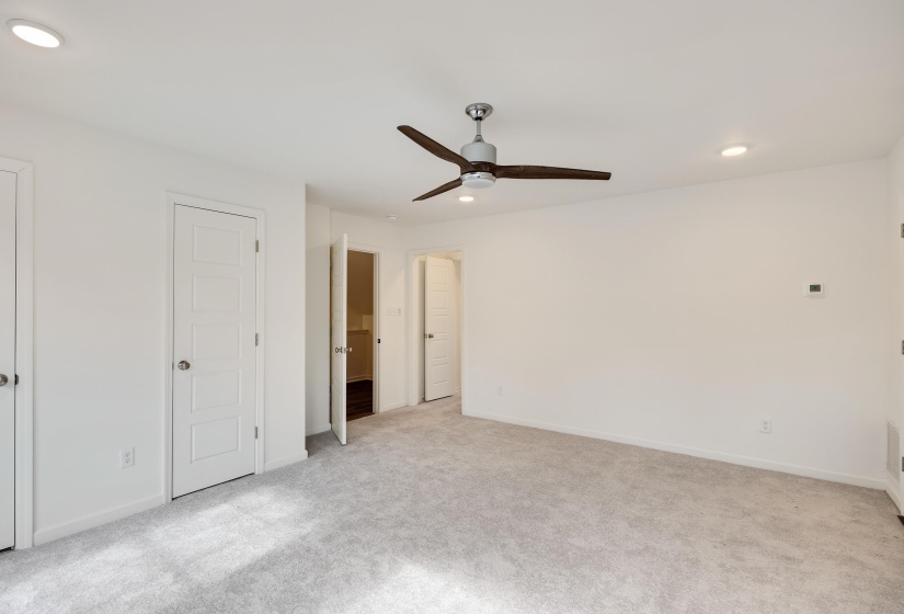 Spacious room featuring light grey carpet flooring, recessed lighting, and a contemporary ceiling fan
