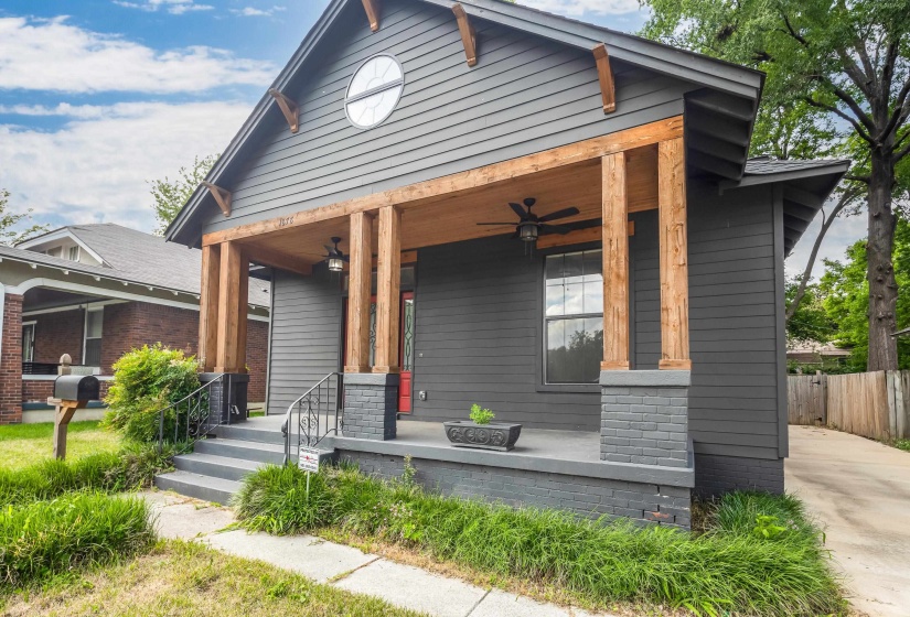 Craftsman-style facade featuring dark gray siding and a covered front porch with natural wood pillars and ceiling