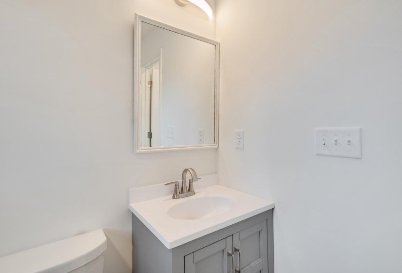 Bathroom vanity featuring a light gray cabinet, white countertop, and an integrated sink with a brushed nickel faucet