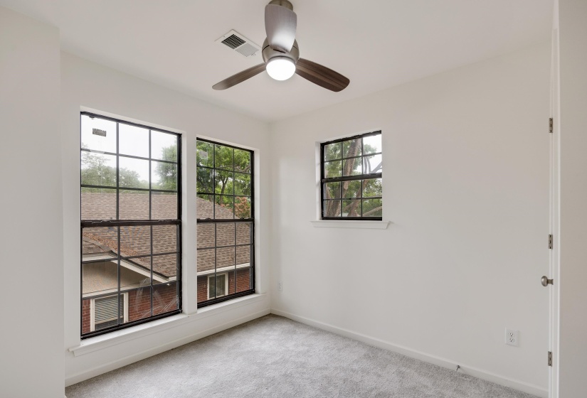 Carpeted room featuring multiple windows, a ceiling fan with integrated lighting, and white walls