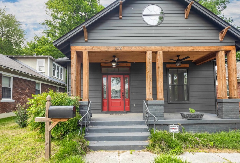 Craftsman-style exterior with dark gray siding, featuring a covered porch with substantial wood pillars