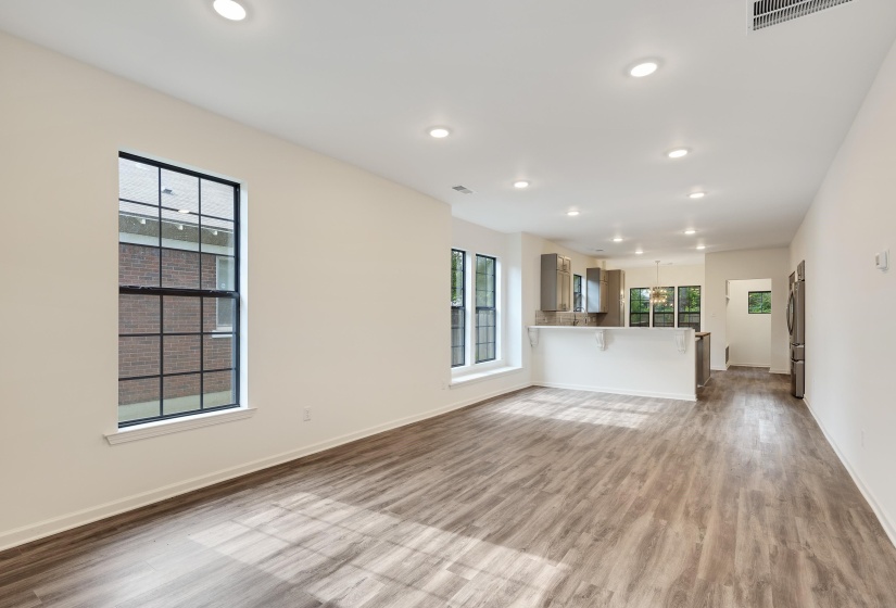 Open-concept living area featuring wood-finish flooring, recessed lighting, and a kitchen with a breakfast bar