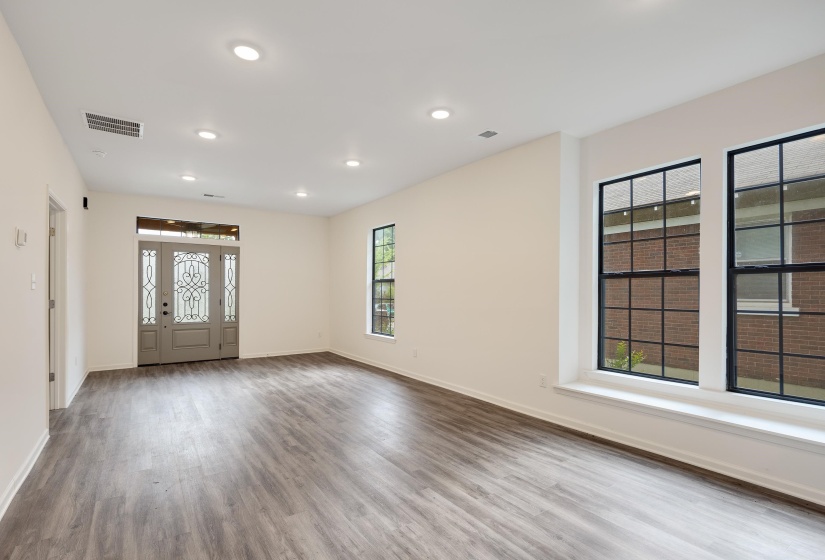 Spacious interior featuring wood-finish flooring, recessed lighting, and a decorative frosted glass entry door