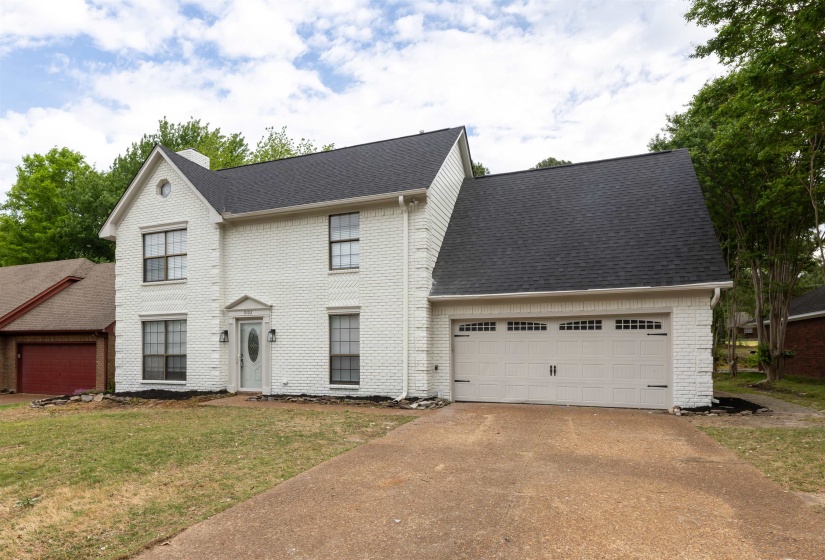 White brick exterior with a dark asphalt shingle roof