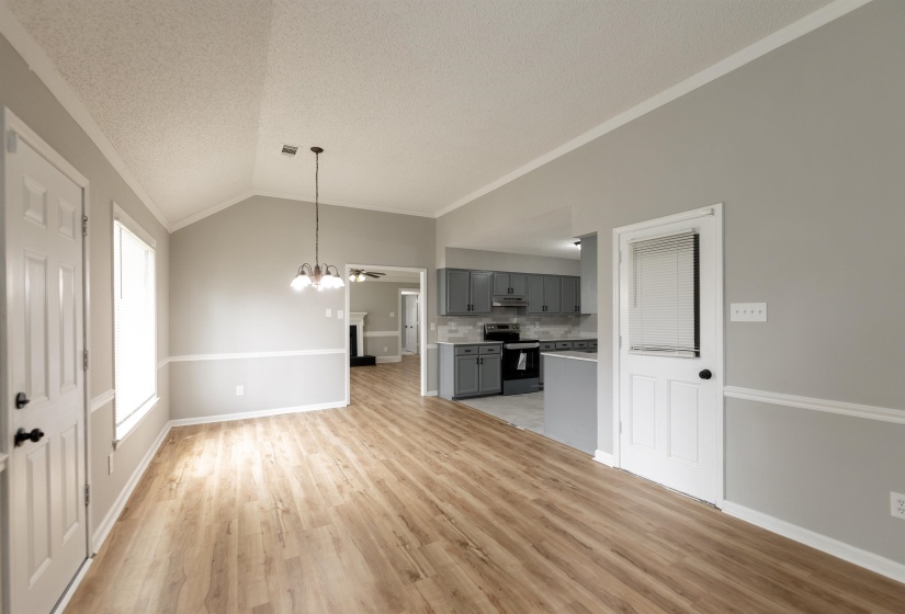 Spacious room featuring wood-finish flooring, vaulted ceiling, and chair rail molding
