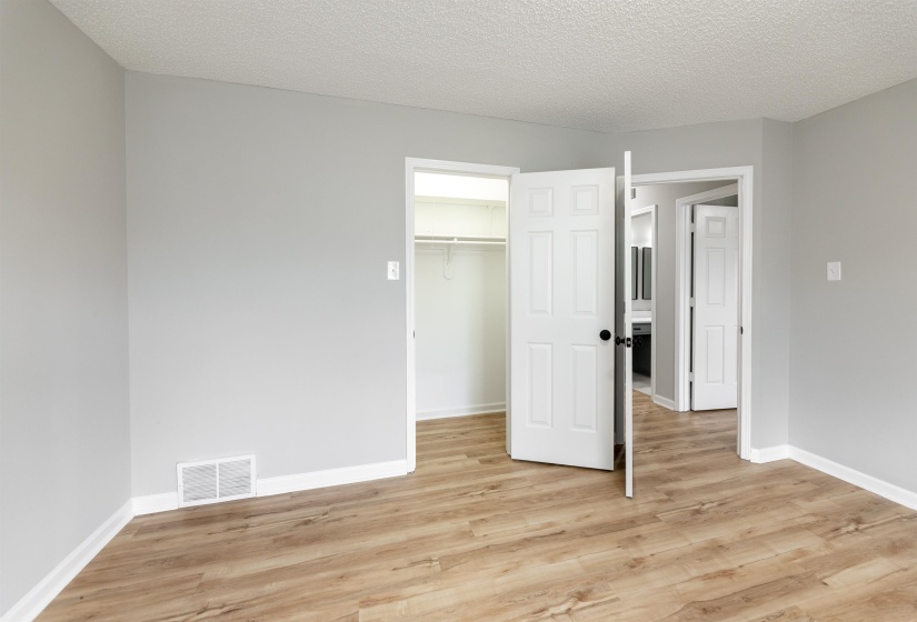 Room featuring light gray walls, wood-finish flooring, white baseboards, and a white popcorn ceiling