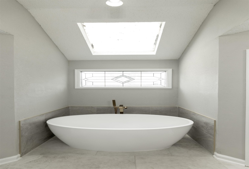 Freestanding soaking tub with a modern brass floor-mounted faucet