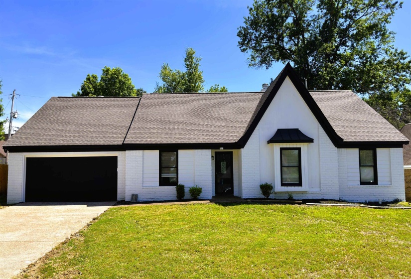 White brick exterior with a dark shingle roof and contrasting black trim