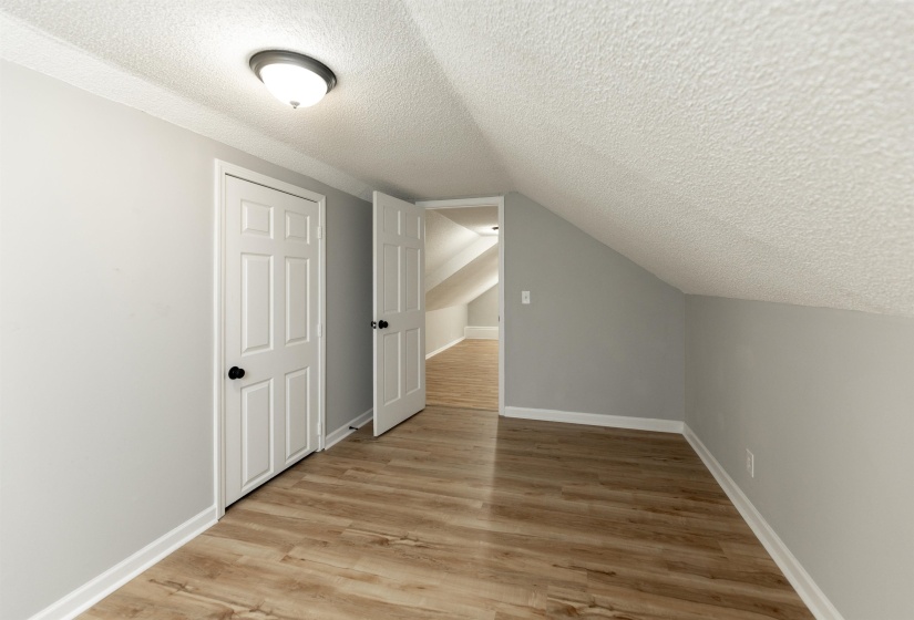 Room featuring wood-finish flooring, light gray walls, white baseboards, and a semi-flush mount ceiling light