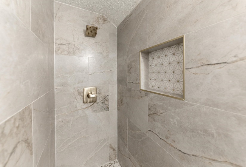Shower stall featuring large format grey tile with natural veining
