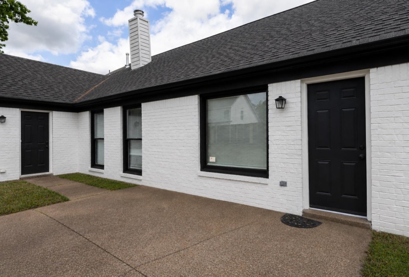 White brick exterior with a dark shingle roof and black trim