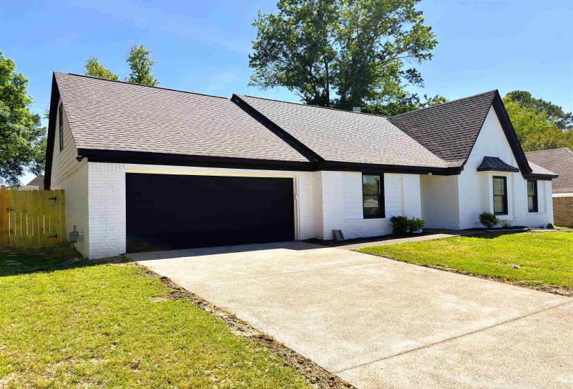 White brick exterior with black trim, featuring a dark asphalt shingle roof