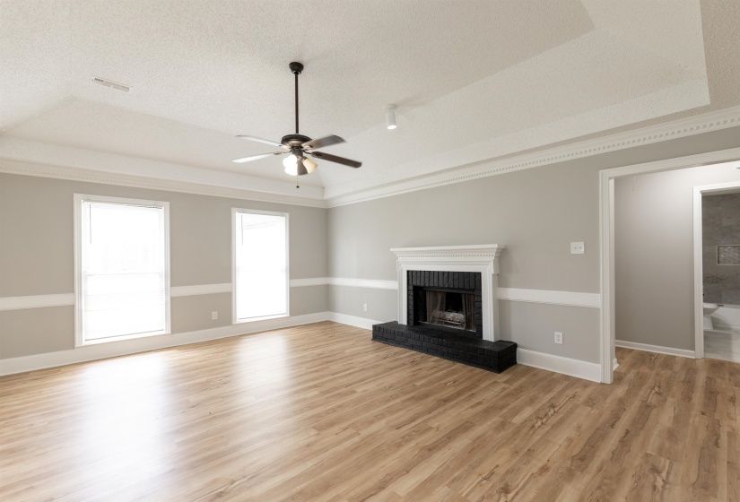 Spacious living area featuring wood-finish flooring, a tray ceiling, and crown molding