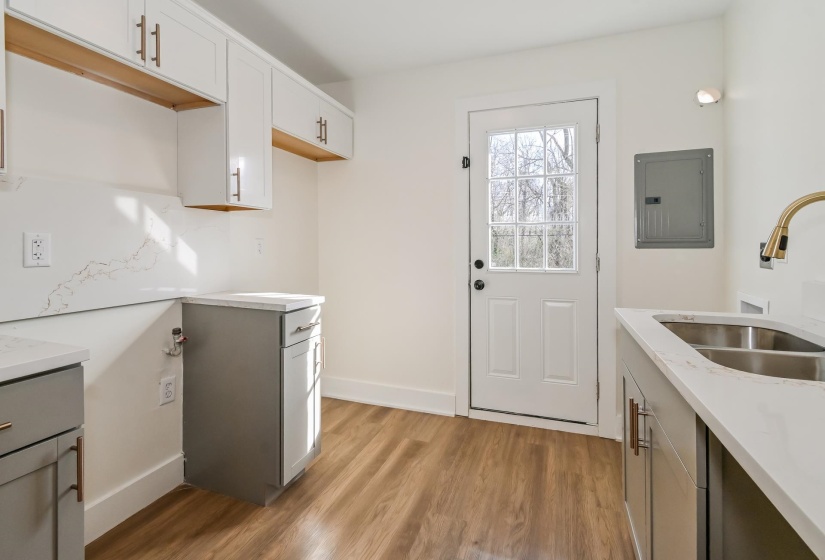 Wood-finish flooring complementing a white door with multiple glass panes