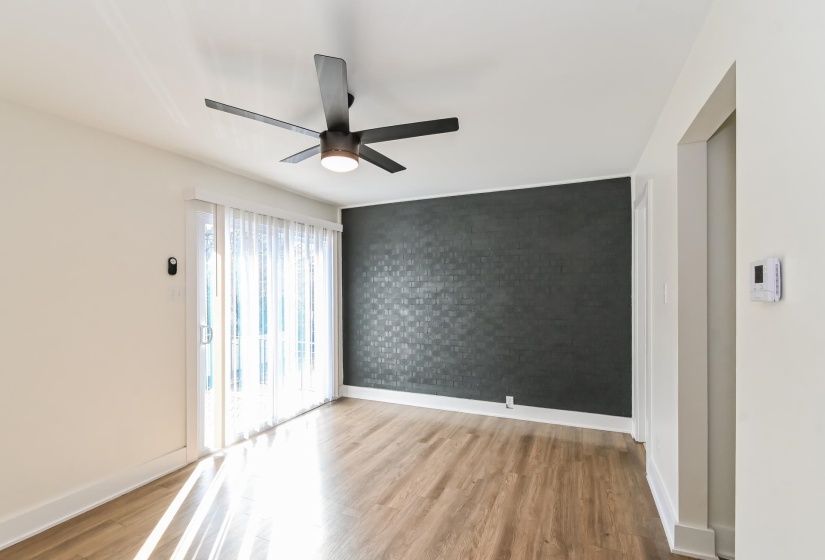 Living area featuring wood-finish flooring, a contemporary ceiling fan, and a sliding glass door