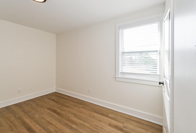 Bright room featuring wood-finish flooring, white baseboards, and a single window with white blinds
