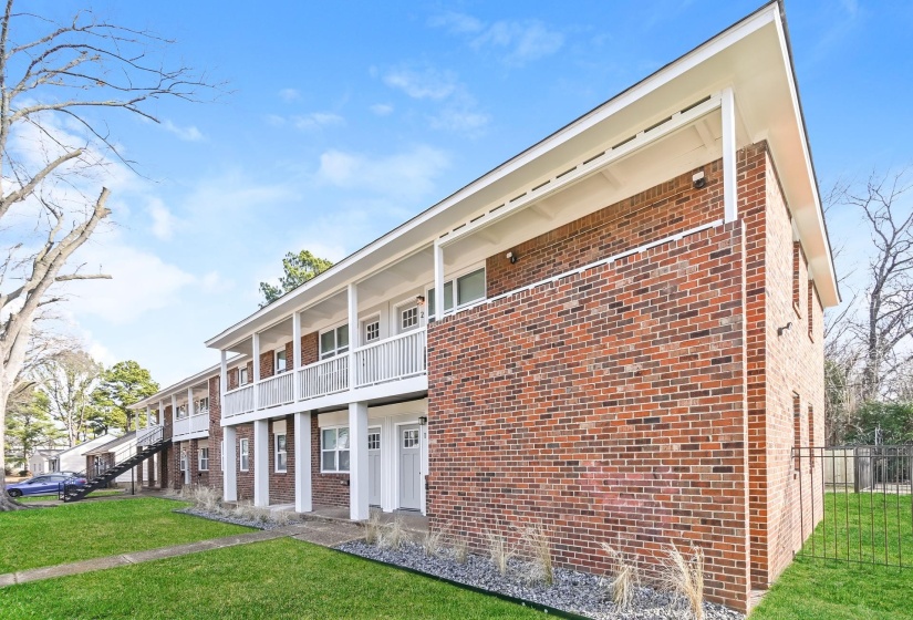 Brick apartment building featuring multiple units with individual entrances and balconies