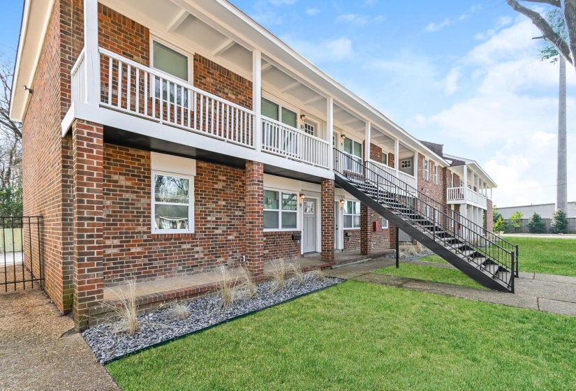 Brick exterior building featuring white balconies and black external staircases