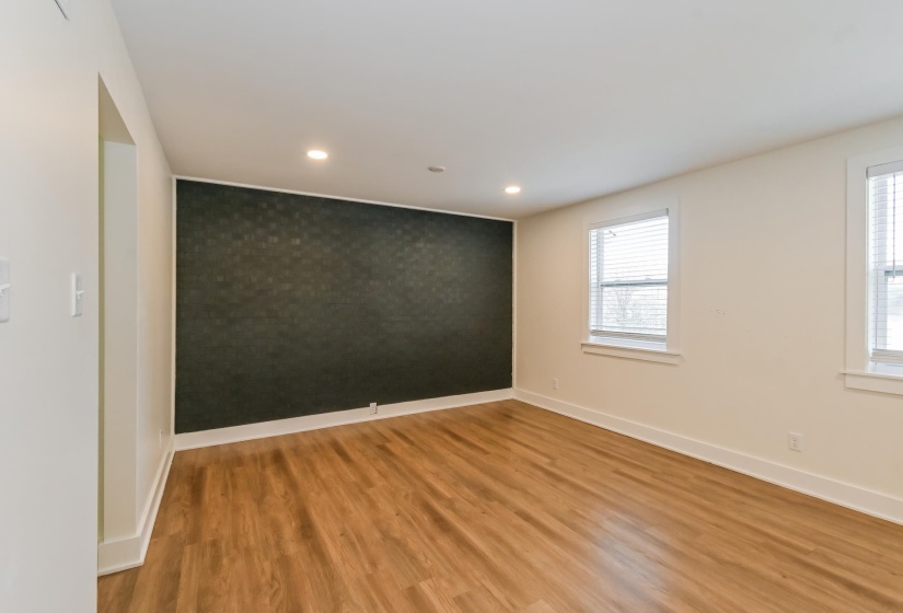 Spacious room featuring wood-finish flooring, recessed lighting, and a dark accent wall