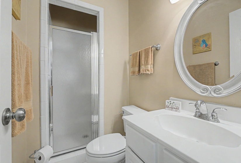 Full bathroom featuring a shower stall with a frosted glass door, a toilet, and a vanity with an integrated sink