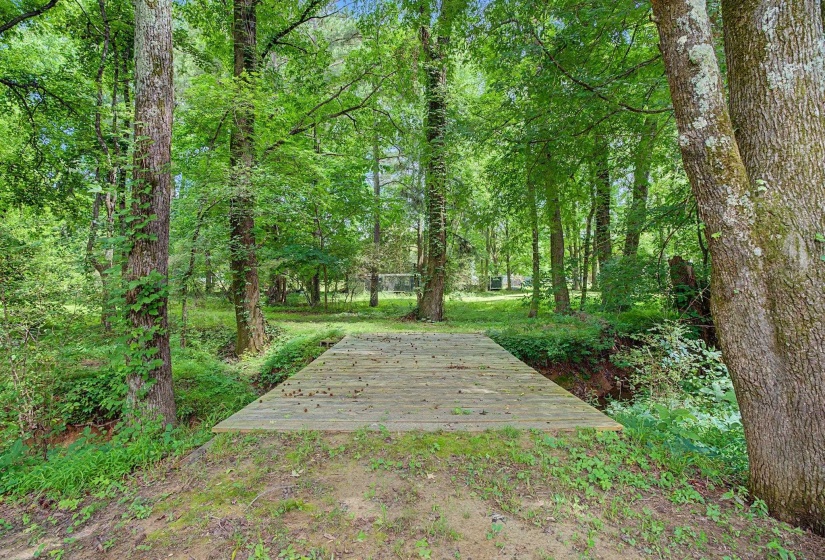 Wooden bridge spanning a little creek surrounded by mature trees and lush greenery