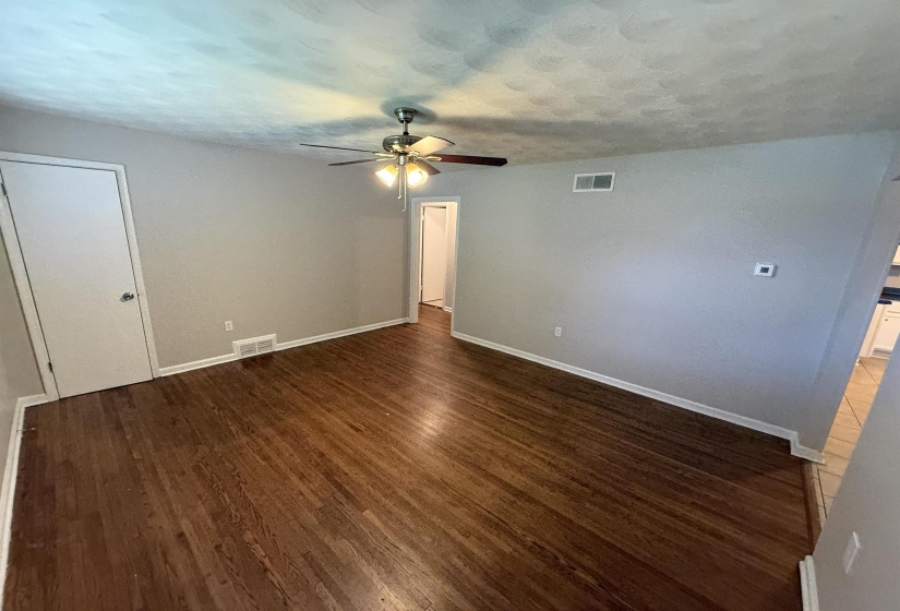 Spacious interior featuring wood-finish flooring, a ceiling fan with integrated lighting, neutral wall paint, and white trim